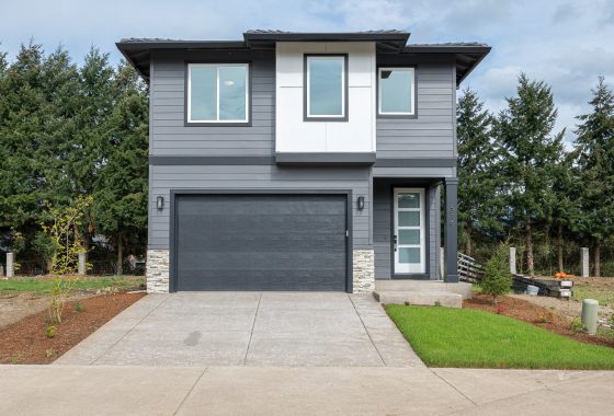 A modern two-story home with a gray facade, double garage, and clean landscaping.