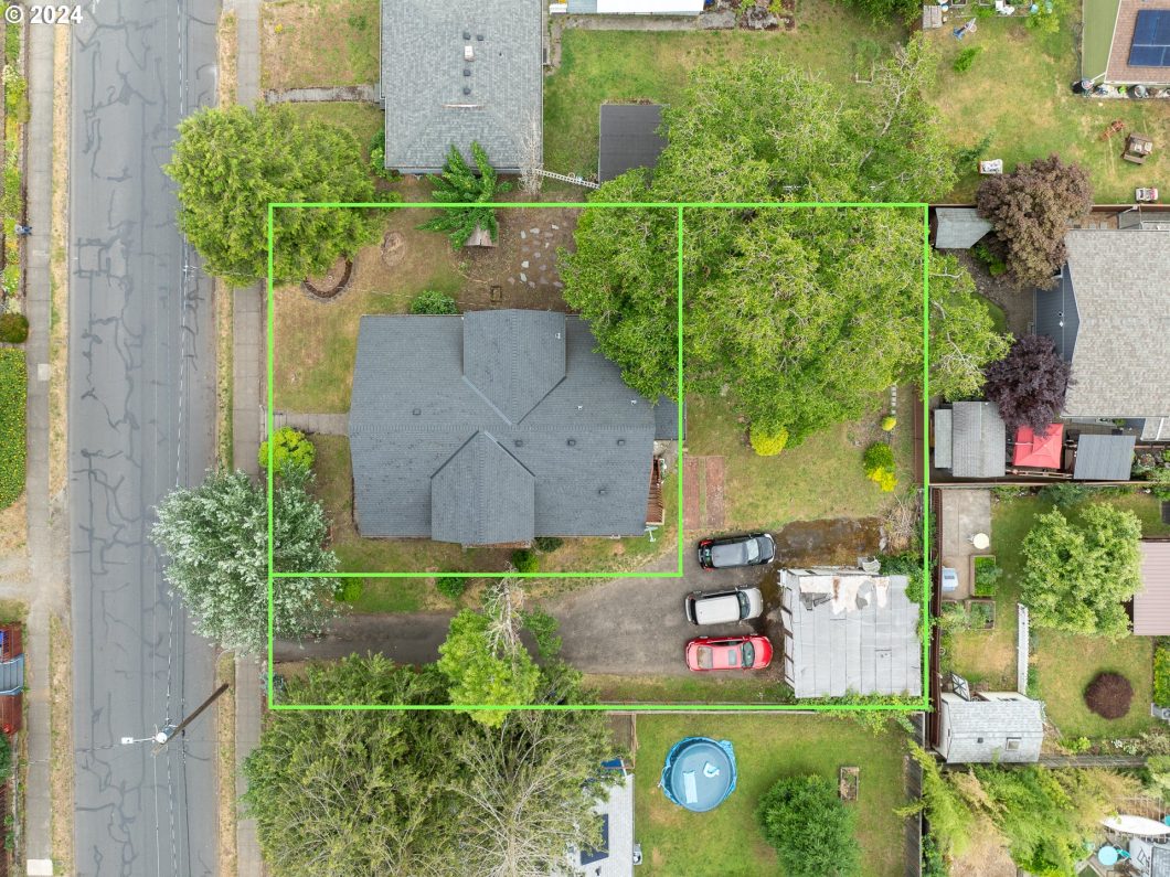 Aerial view of a residential property with outlined boundaries, showing a house, trees, and surrounding yards.